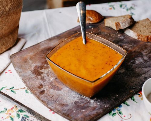 front-view-orange-peppered-soup-inside-plate-salted-tasty-with-spoon-along-with-bread-loafs-meal-liquid-brown-desk_140725-16074