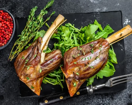 stew-goat-shanks-marble-board-with-arugula-black-table-top-view_89816-19398