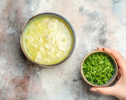 top-view-dushbara-dumplings-soup-greens-bowl-female-hand-nude-surface-with-copy-space_140725-62517